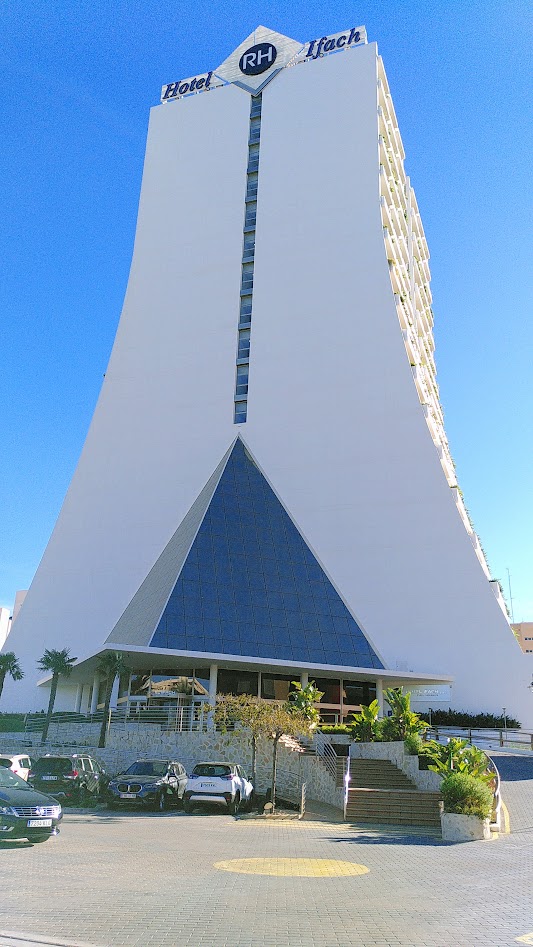 The RH Hotel Ifach, a vaguely triangular shaped white building.